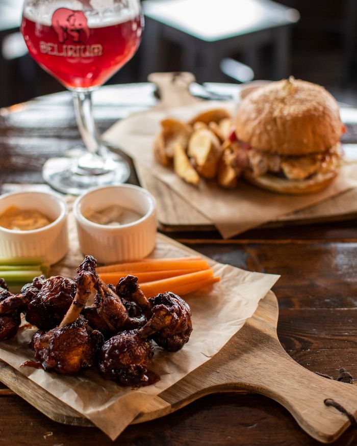 Close-up of delicious chicken wings, burger, and craft beer on a wooden table.