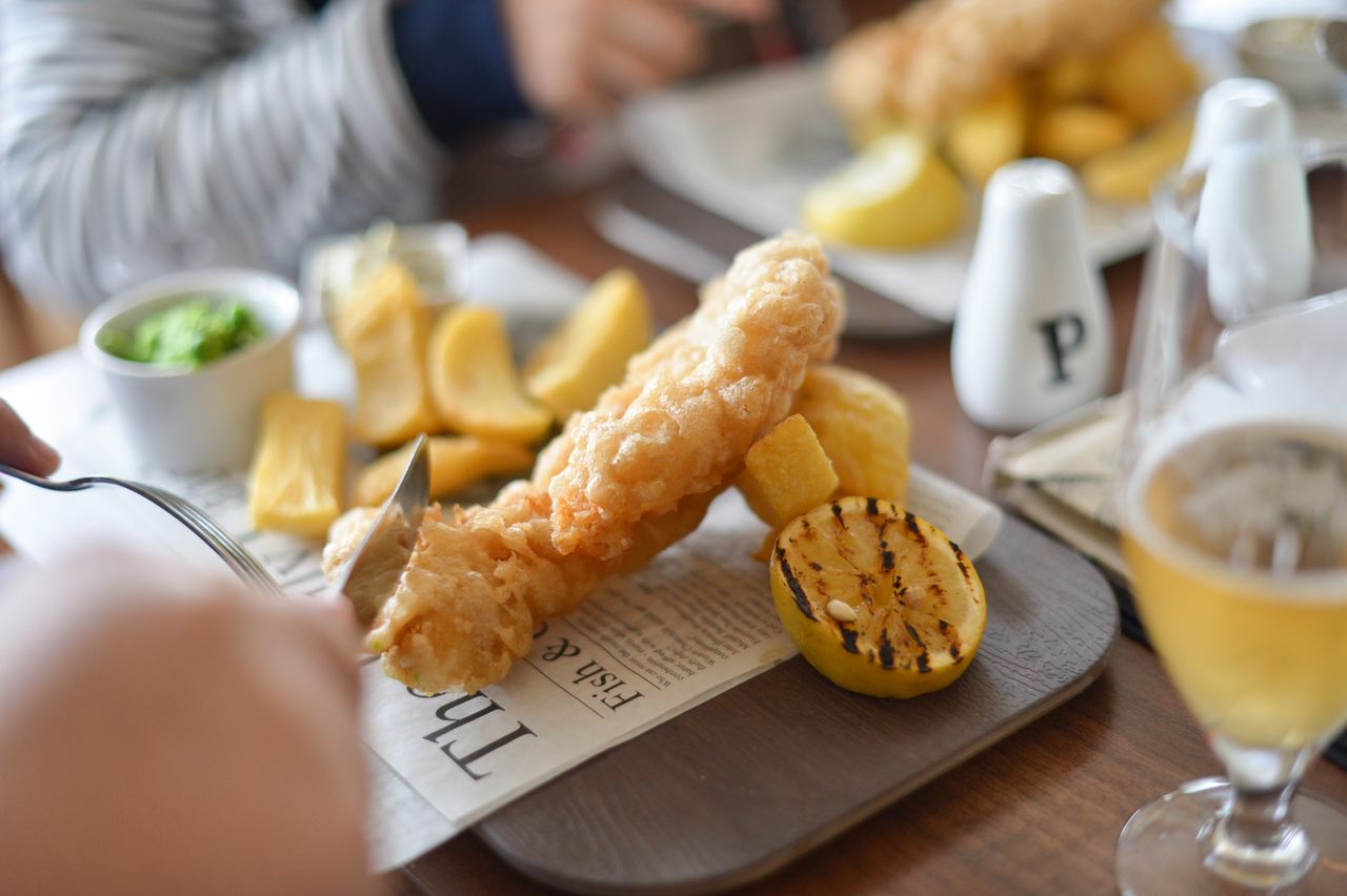 Close-up of crispy fish and chips with garnish, ideal for food photography.