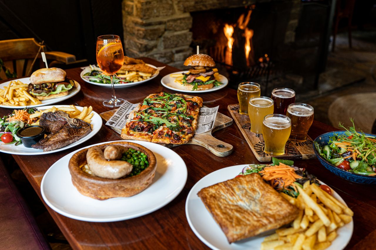A delectable spread of Australian cuisine including burgers, pizza, and more in a cozy indoor setting.